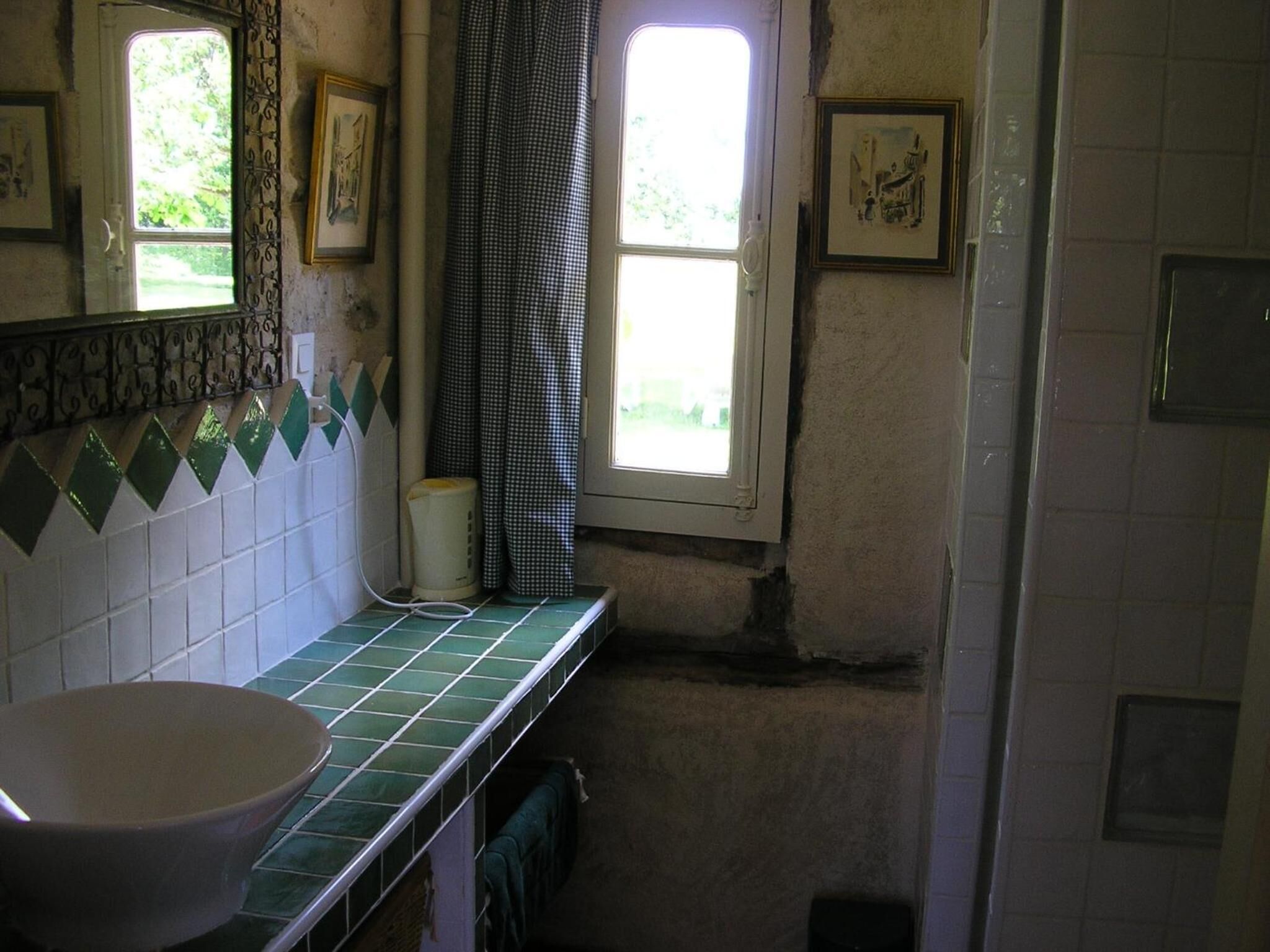 Une salle de bain avec un lavabo, une fenêtre et un miroir.