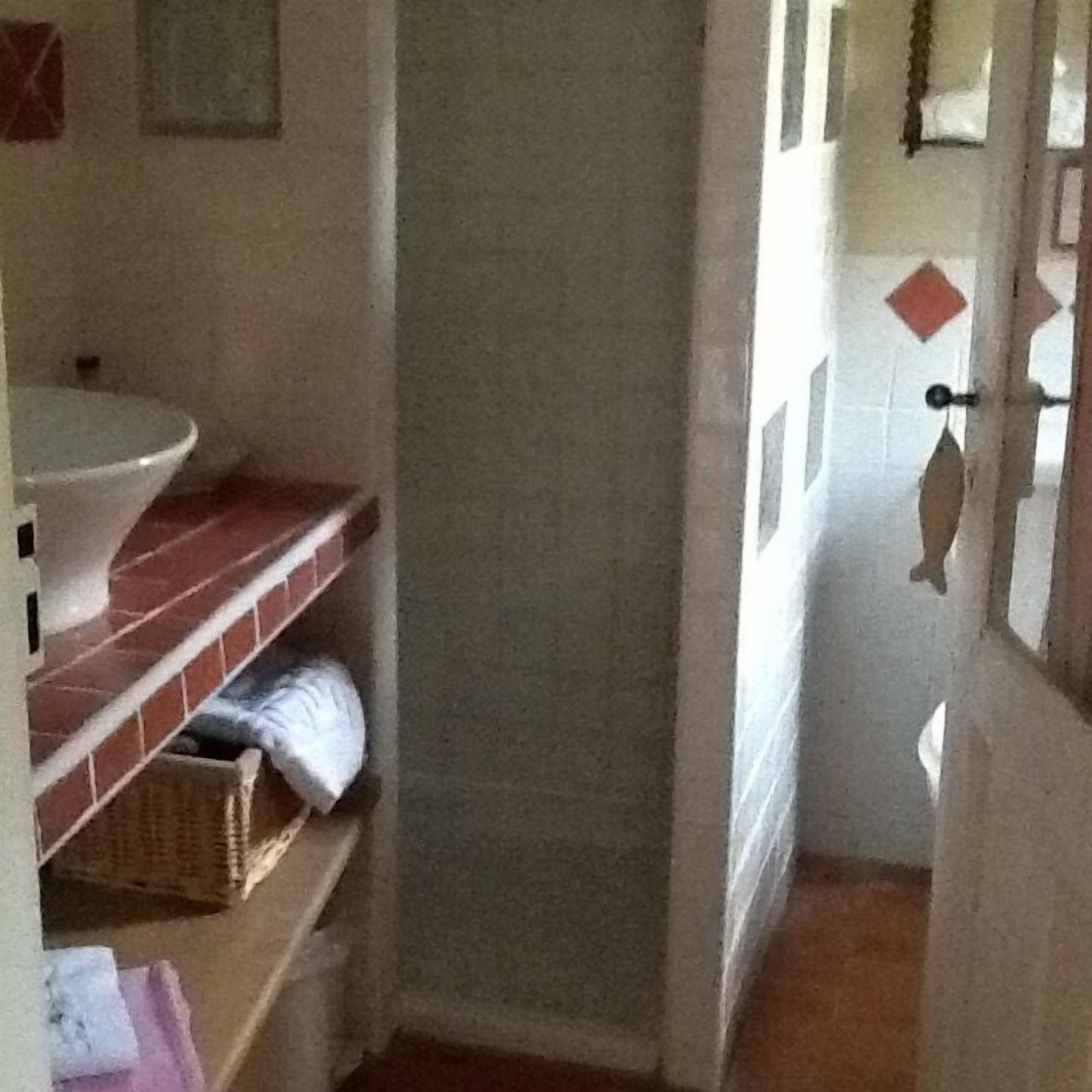 A bathroom with a white sink, red-tiled shelves, and a white towel hanging on the wall.
