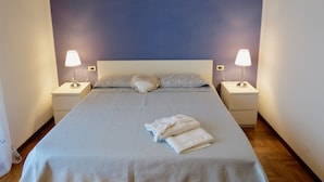 A neatly made bed with a patterned bedspread and pillows, two bedside lamps, and a decorative ceiling light fixture. - Villa Anastasye (Predore)