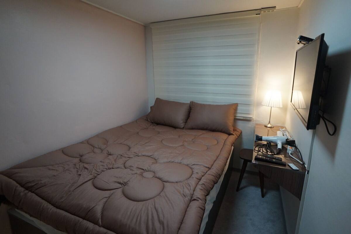 Ein Schlafzimmer mit einem Bett, einem Nachttisch, einer Lampe und einem Fernseher.