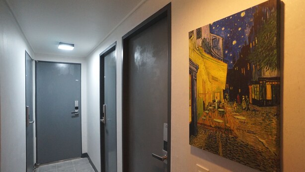 A hallway with grey doors and a painting of a night scene on the wall. - Blue Mansion Guesthouse (Seoul)
