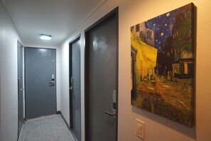 Un pasillo con puertas grises y un cuadro de una escena nocturna en la pared.