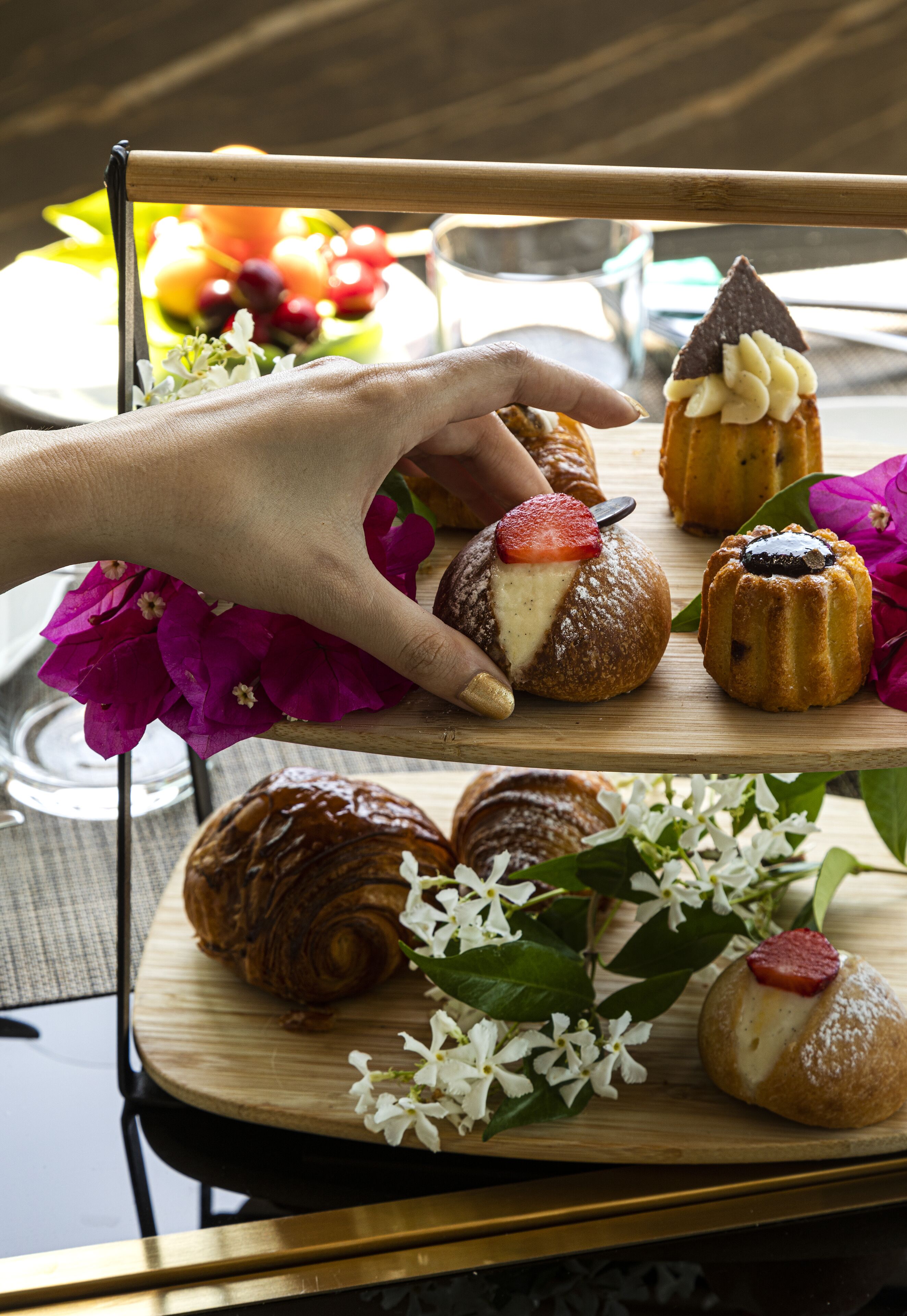 A tray of pastries on a table with a hand reaching for one.