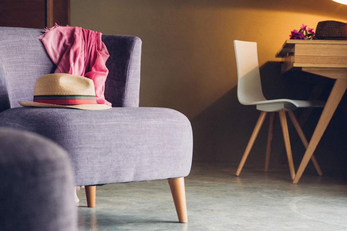 A modern living room with a grey sofa, a wooden dining table, and a hat on the sofa.