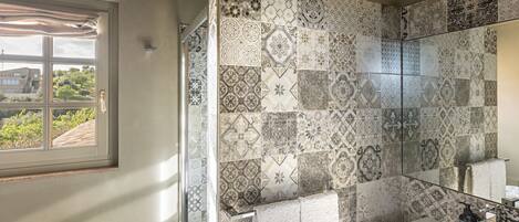 A bathroom with patterned tiles, a window, and a sink with a mirror.