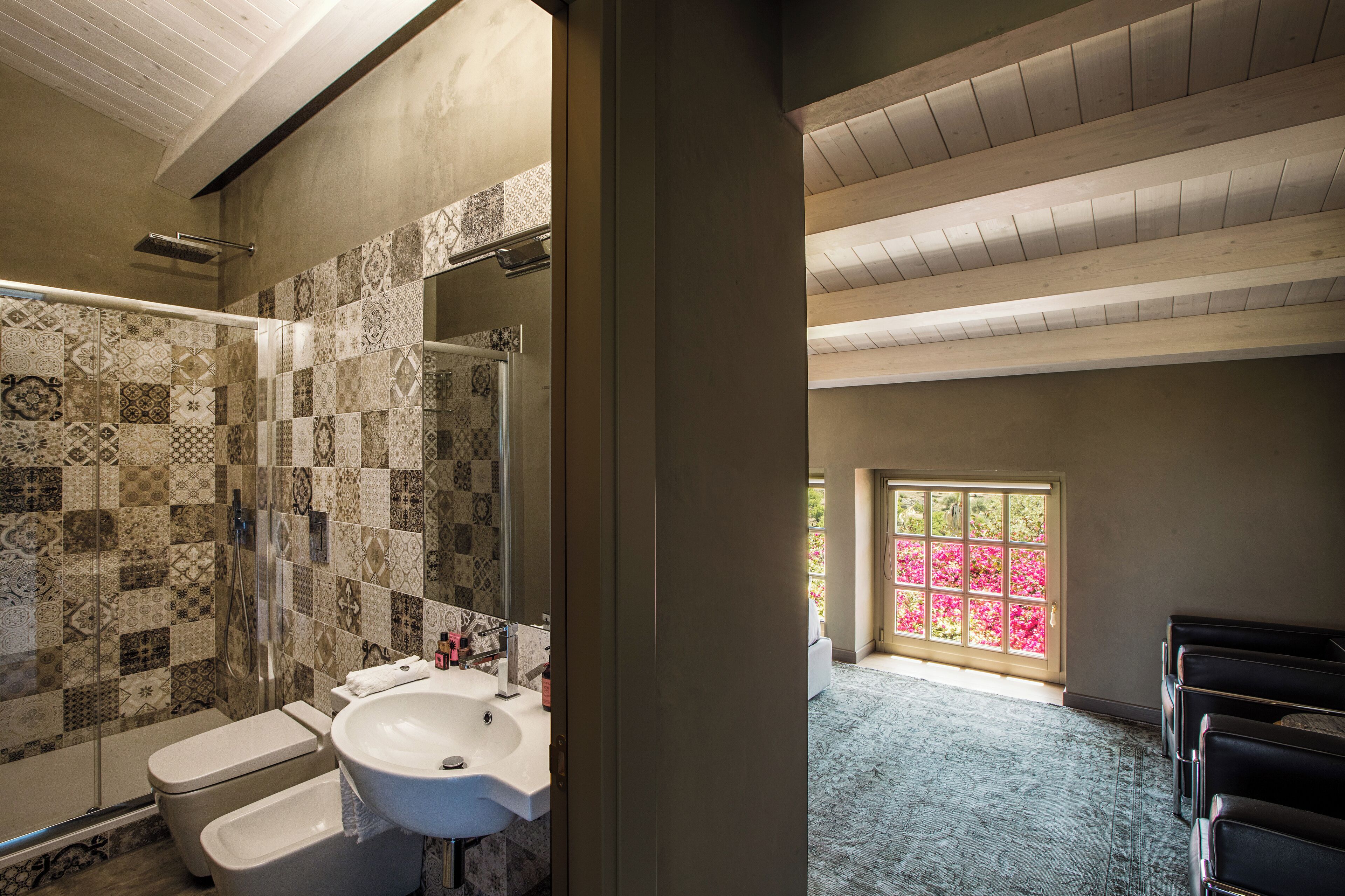 A bathroom with a checkered tile wall, a white sink, and a shower.