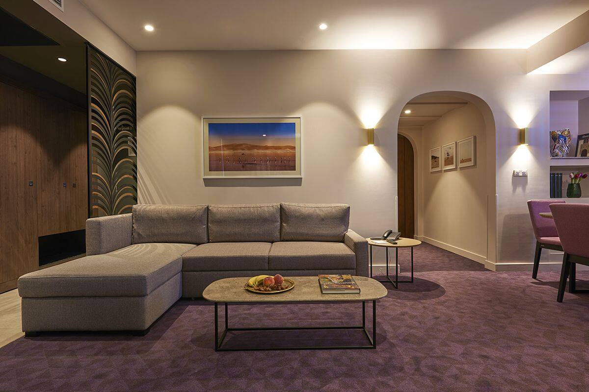 Un salon moderne avec un canapé d’angle, une table basse et un tableau accroché au mur.