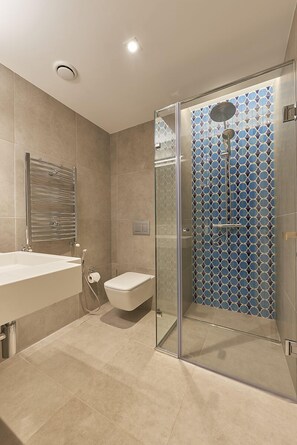 A modern bathroom with a glass-enclosed shower, a white sink, and a toilet. - M Suite Hotel (Algiers)