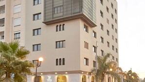 A modern hotel with a prominent glass facade, multiple floors, and a visible entrance with a staircase. - M Suite Hotel (Algiers)