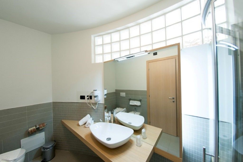 A modern bathroom with two sinks, a mirror, and a shower area.