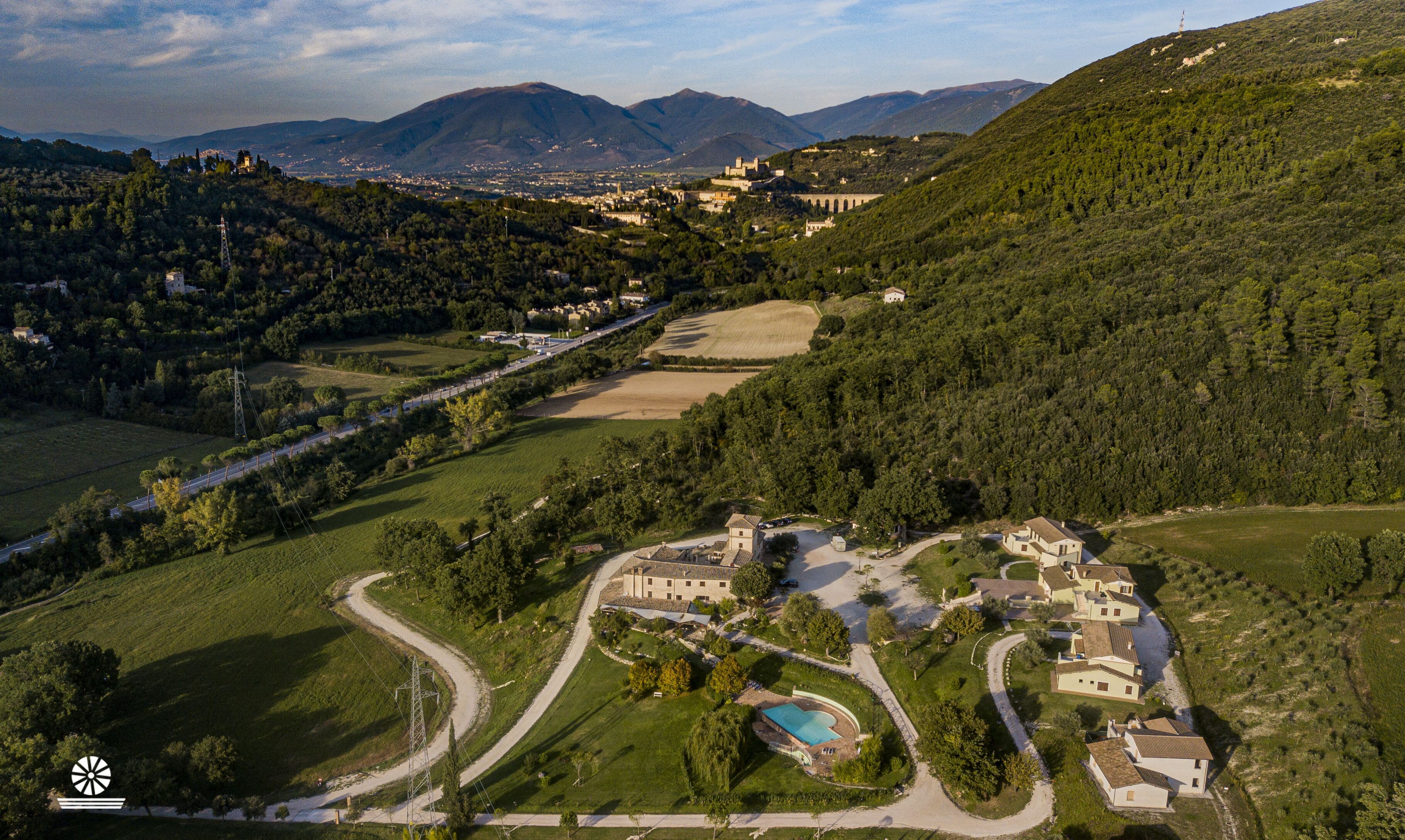 Vista aérea de una zona rural con un complejo de edificios grande, rodeado de campos y bosques.
