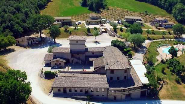 Vista aèria d'una zona residencial amb diversos edificis, una piscina i vegetació als voltants.