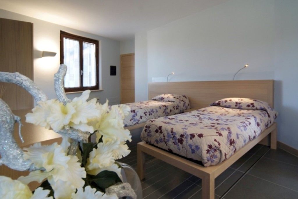 A bedroom with two single beds, a wooden headboard, and a decorative mirror with flowers.