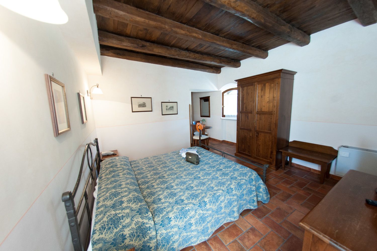 Un dormitorio con cama, armario de madera y un banco.