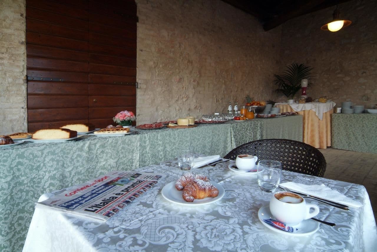 Une table de petit-déjeuner dressée avec des viennoiseries, du café et des journaux.