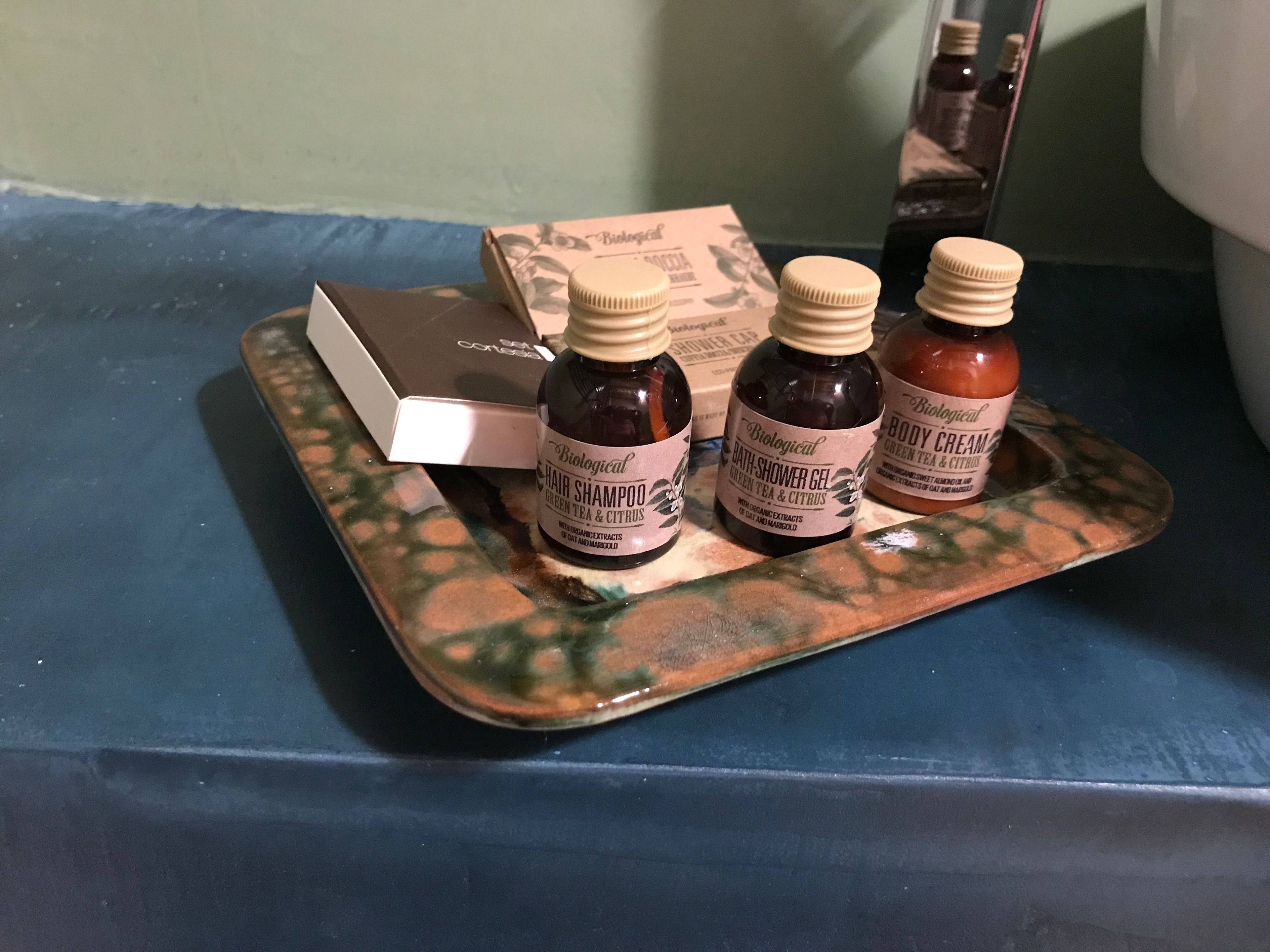 Una bandeja con tres botellas de champú y una caja de gorro de ducha.