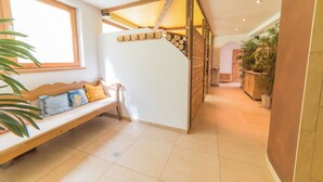 A modern interior with a wooden bench, a staircase, and a plant.
