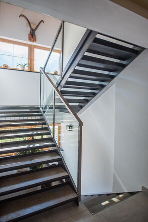 A modern staircase with glass railings and metal supports, leading to an upper floor. - Pension Sprenger (Curon Venosta)