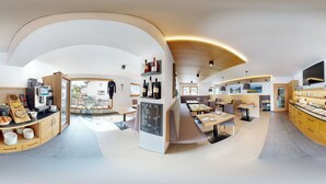 A modern dining area with curved wooden cabinetry, built-in seating, and a central island with a chalkboard menu.