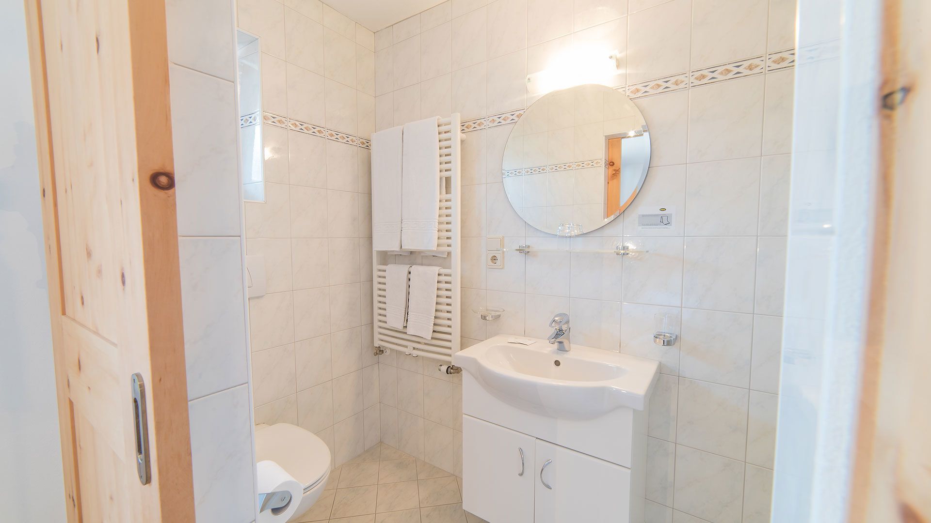 A small, clean bathroom with a toilet, sink, and mirror.