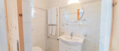 A small, clean bathroom with a toilet, sink, and mirror.