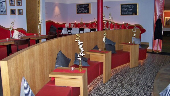 Un restaurante con cabinas, cojines rojos y piso estampado.