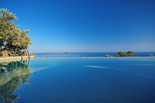 Una piscina al aire libre, sombrillas, sillones reclinables de piscina