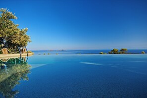 A clear blue infinity pool with a view of the sea and distant islands. - The Infinity 180 Luxury Suites - Adults Only (Alonissos)
