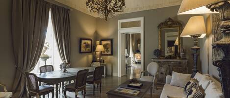 A dining area with a round table and chairs, a chandelier, and a sofa with cushions.