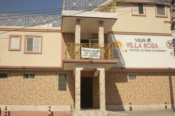 A building with a sign for "Villa Rosa Hotel & Restaurant" and a balcony with a sign for "Special Bouyon Tét Kabrí".