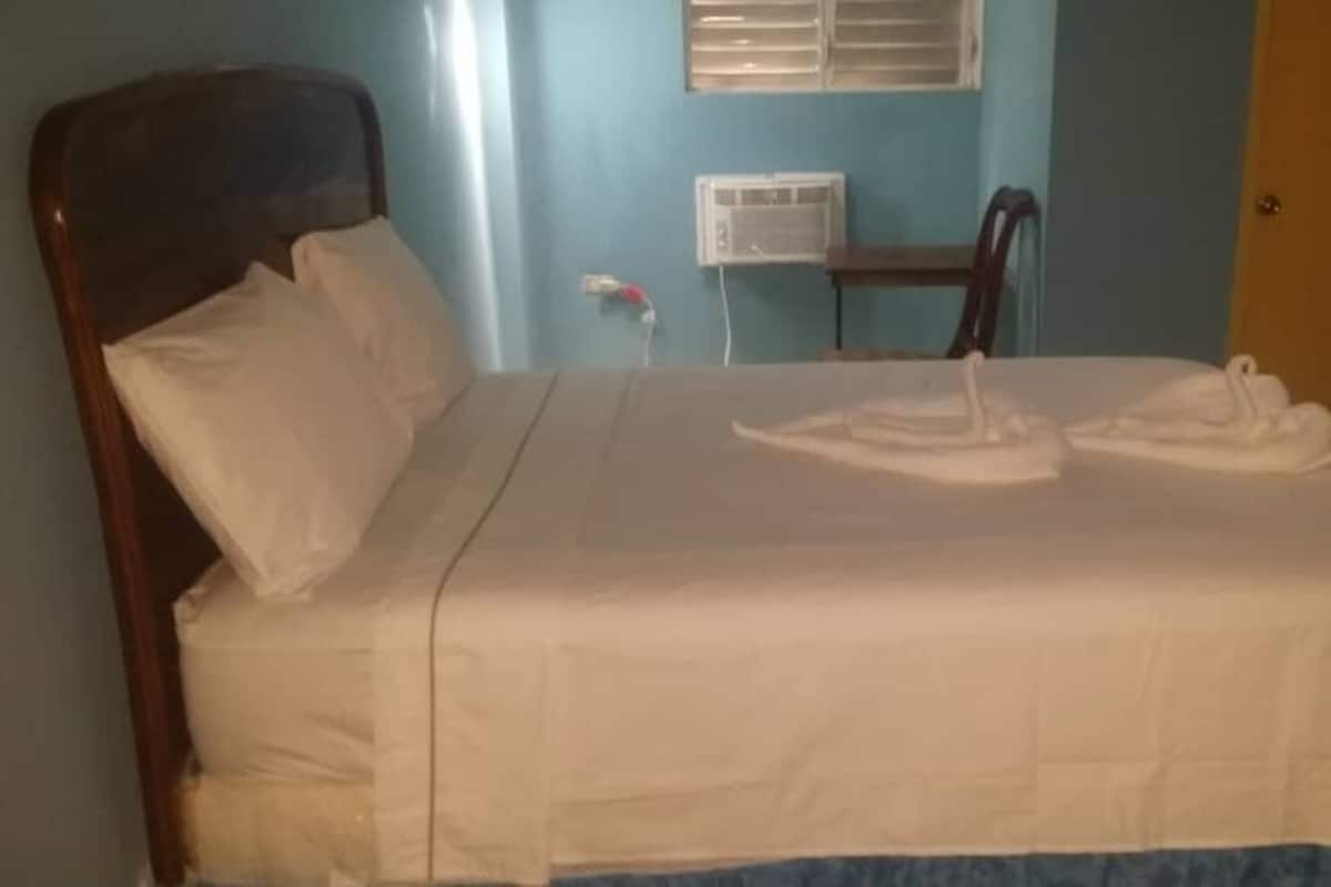 A neatly made bed with white linens and a blue accent at the foot.