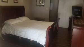 Ein Schlafzimmer mit einem hölzernen Bett, einem Schminktisch, einem Spiegel und einem Fernseher.