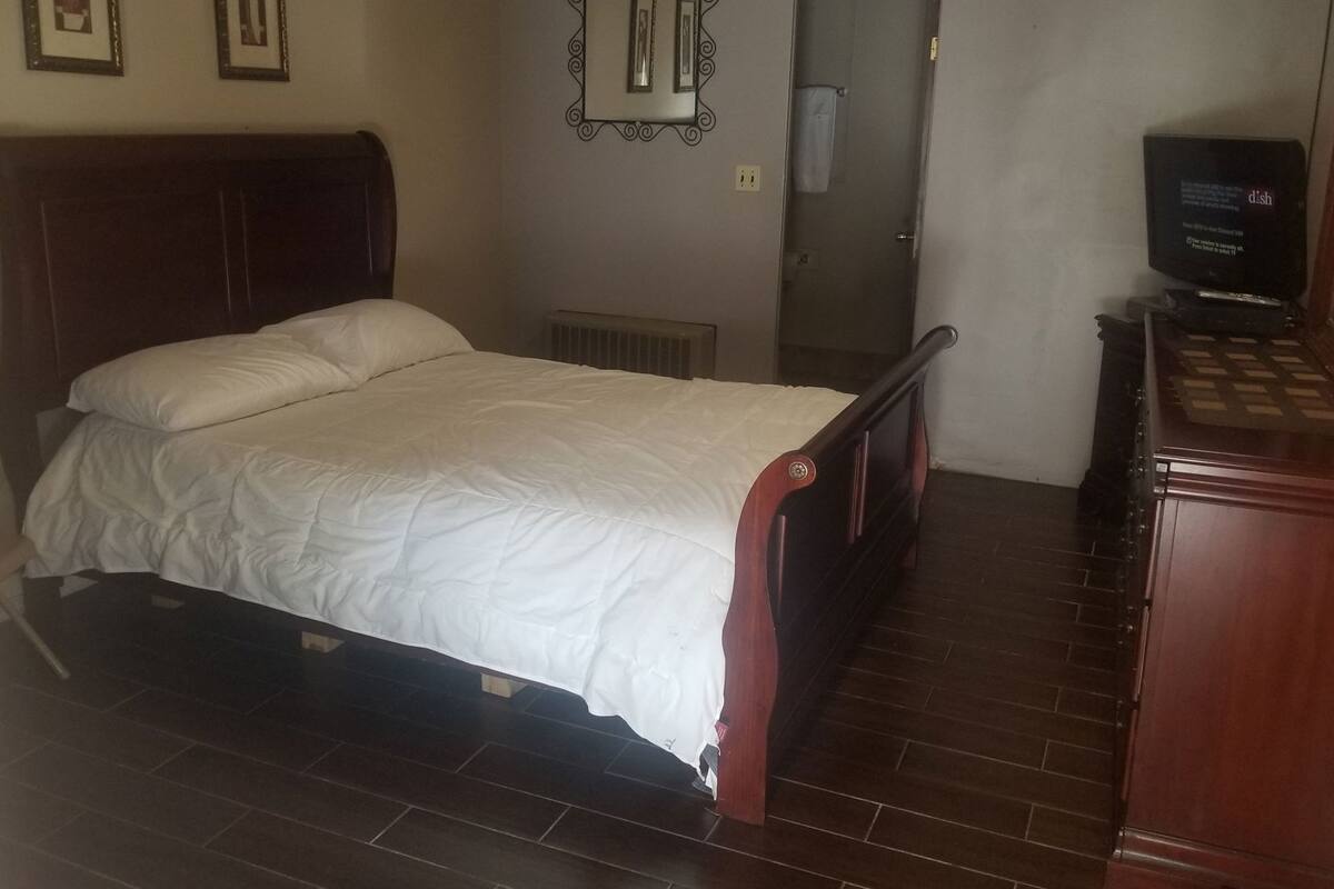 A bedroom with a bed, a dresser, a television, and a door.