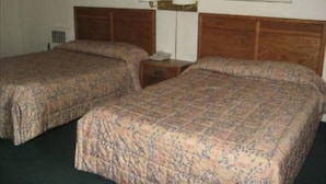 Ein Hotelzimmer mit zwei Einzelbetten, einem Nachttisch mit Lampe und zwei gerahmten Bildern an der Wand.