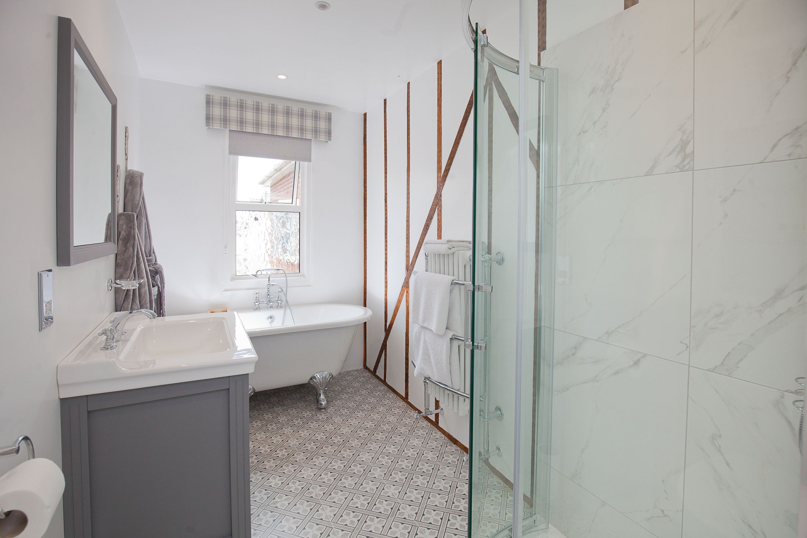Un baño moderno con bañera, cabina de ducha con mampara de vidrio y tocador con espejo.