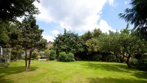 A well-maintained garden with a variety of trees and shrubs, a clear sky, and a neatly trimmed lawn. - The Old House Guesthouse (Salisbury)