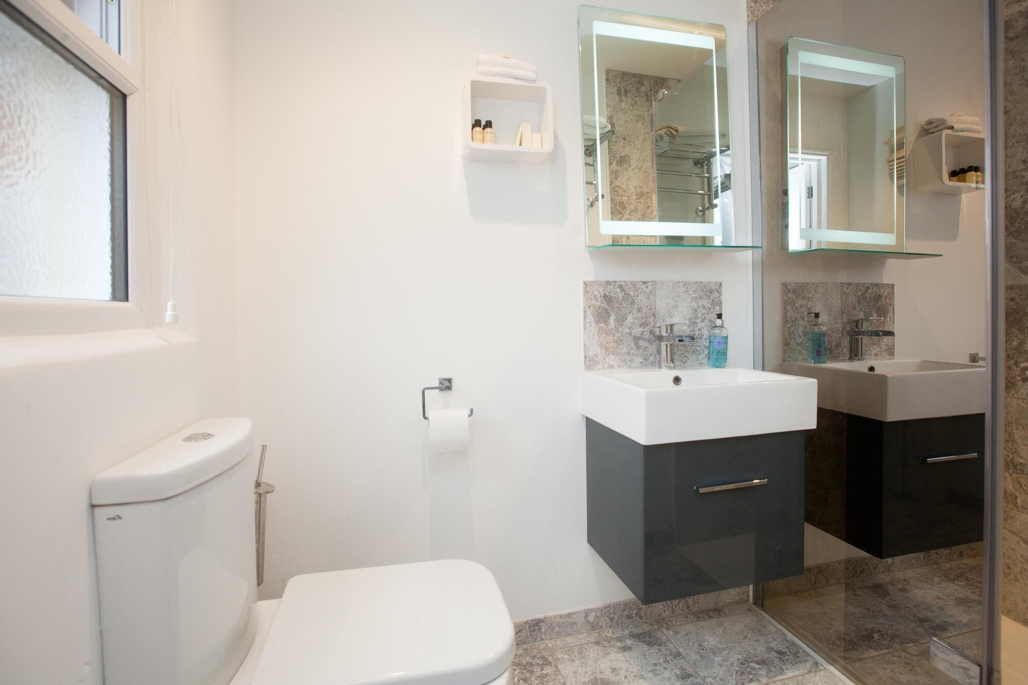 Une salle de bain moderne équipée de toilettes, d’un lavabo et d’un espace douche.