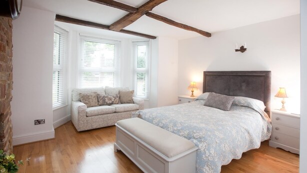 A bedroom with a bed, a bench, and a window seat. - The Old House Guesthouse (Salisbury)