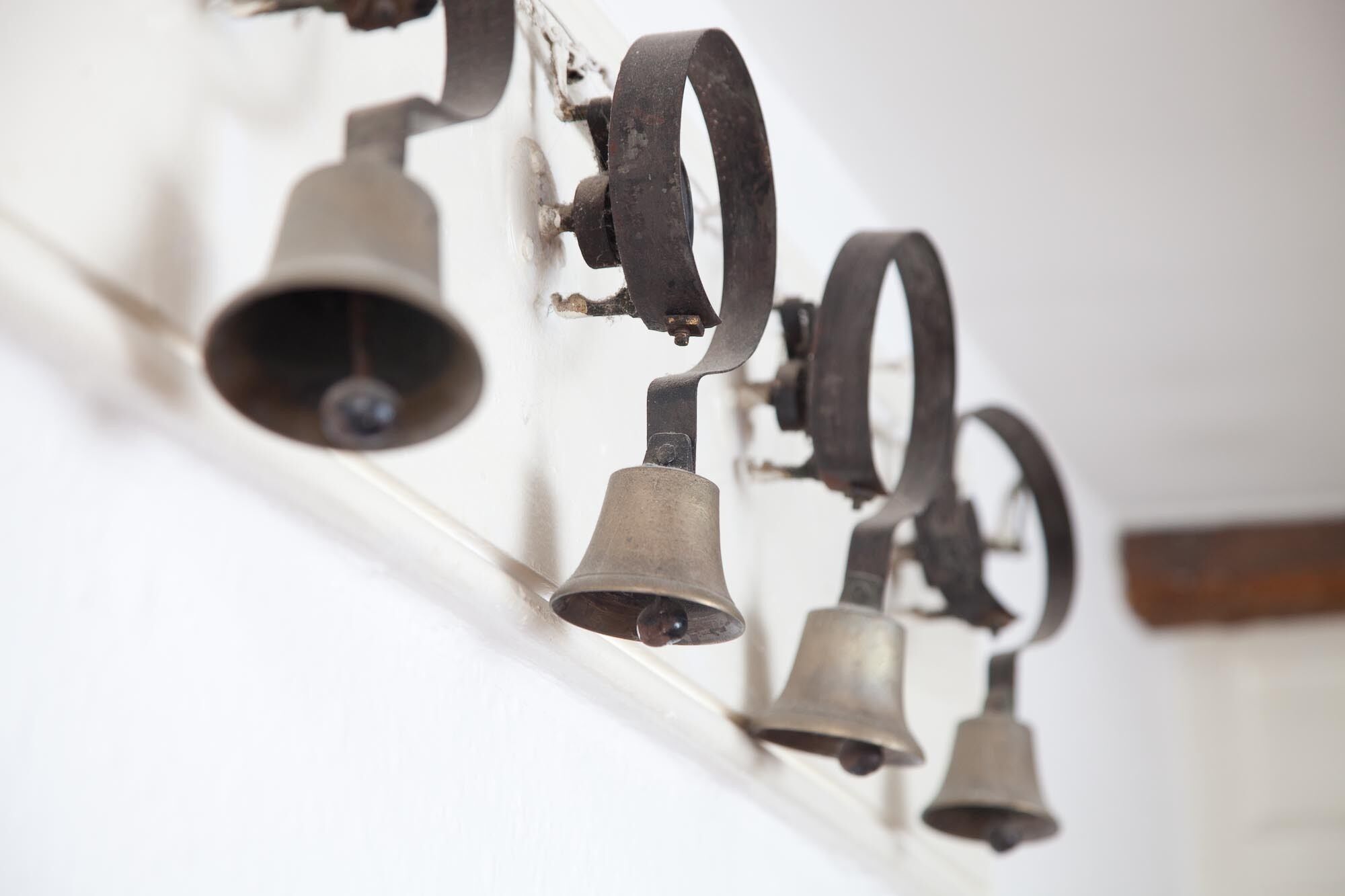 A row of antique bells mounted on a wall.