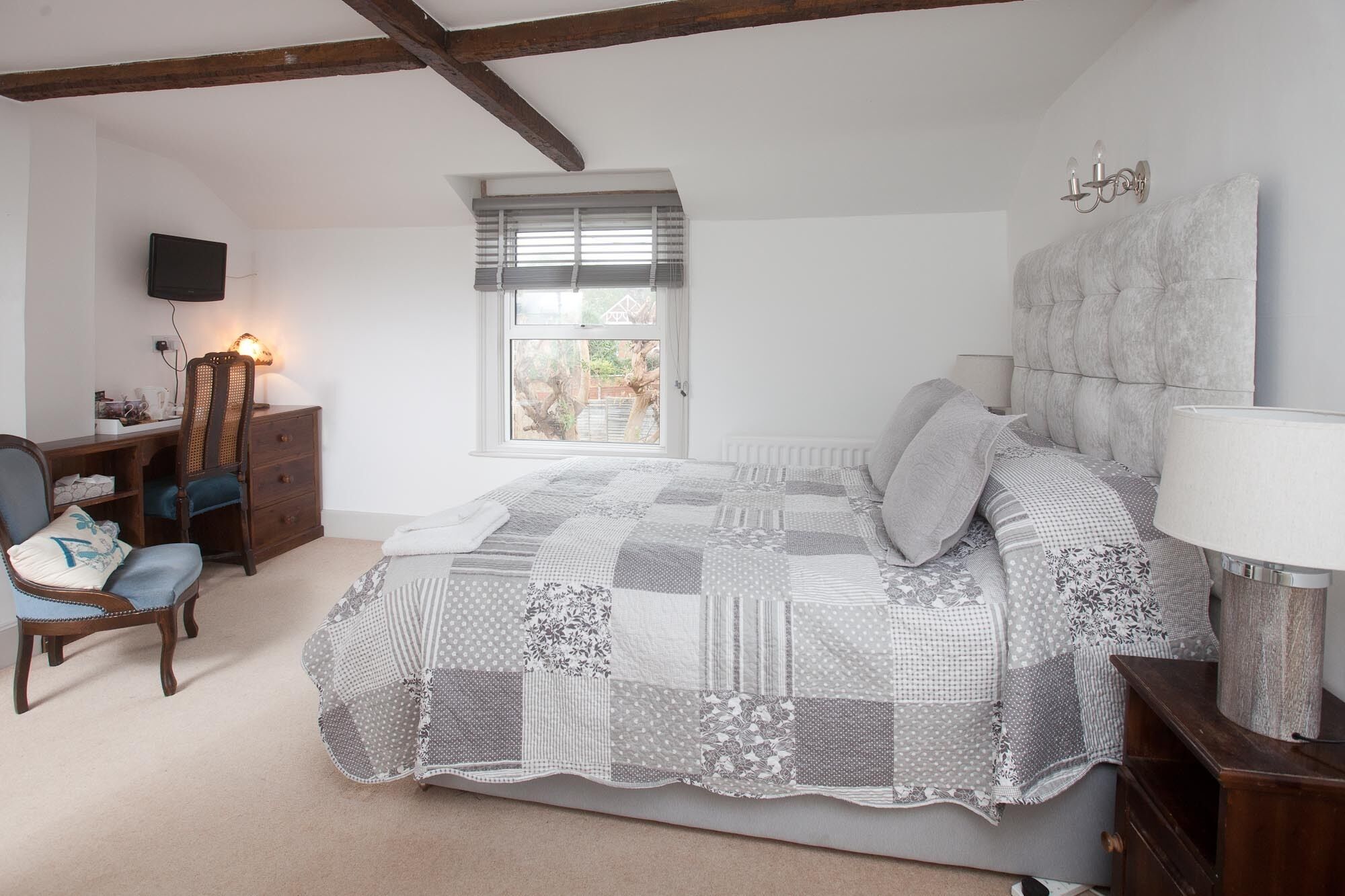 A bedroom with a bed, a desk, a chair, and a window.