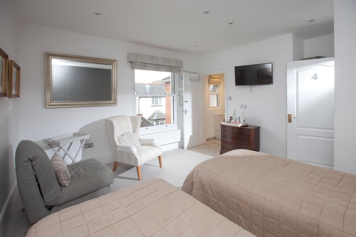 A bedroom with two beds, a desk, a chair, a TV, and a dresser.