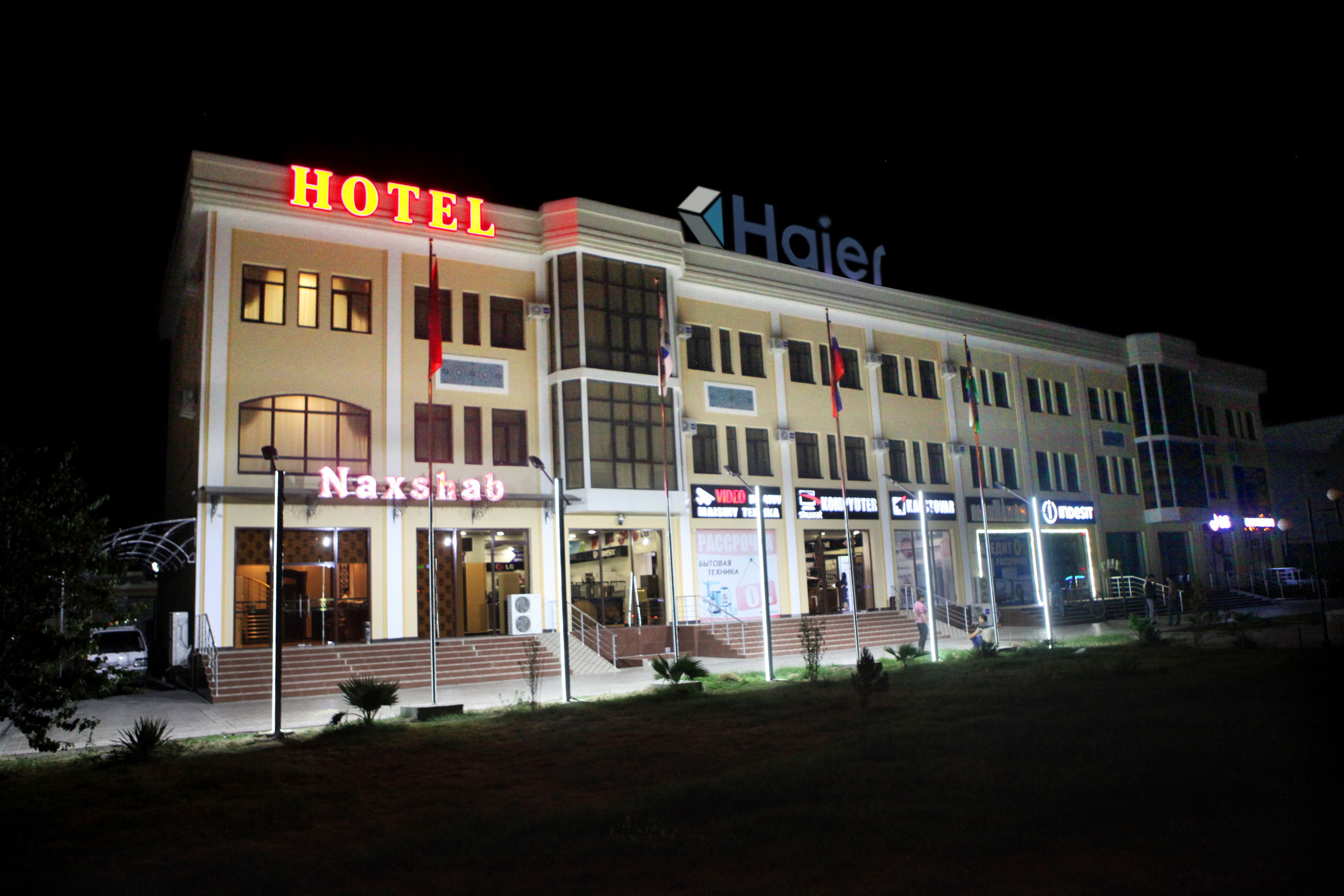 Un hotel con un cartel llamativo que dice 'HOTEL', un cartel 'Haier' y un cartel 'Naxsho'.