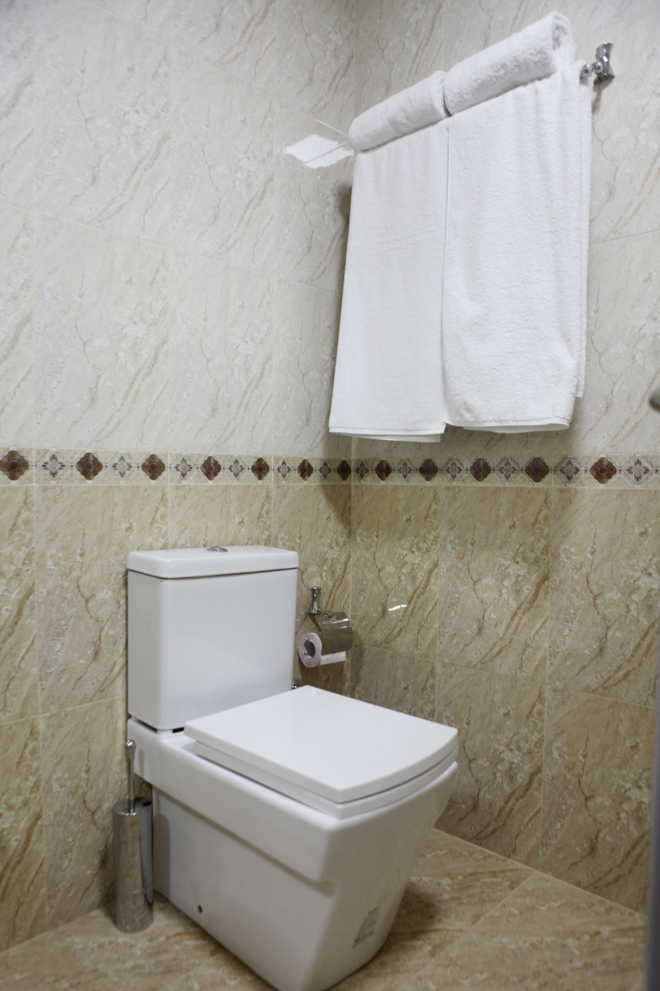 Een badkamer met een toilet, een handdoek aan de muur en een vloer met een marmerlook.