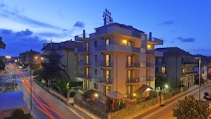A multi-story hotel with balconies and a well-lit entrance. - Hotel Corallo (Orbetello)