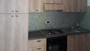 A kitchen with wooden cabinets, a gas stove, an oven, and a sink. - Bed and Breakfast La Mamma (Cittanova)