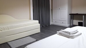 A hotel room with a bed, a white sofa, a TV mounted on the wall, and a wardrobe. - Bed and Breakfast La Mamma (Cittanova)