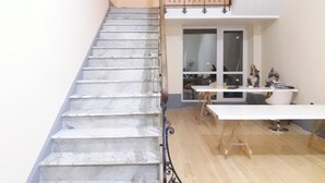 A staircase leading to a balcony with a railing, a white table with chairs, and a window with a view of the interior. - Bed and Breakfast La Mamma (Cittanova)
