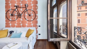 Een kamer met een witte bank, een klein rond tafeltje en een aan de muur bevestigde fiets.