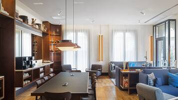 Una habitación de hotel moderna con zona de comedor, sofá y estación de café.