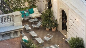 Patio esterno con posti a sedere, luci decorative e piante in vaso.